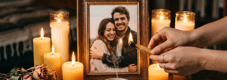 Memorial altar with framed photo of couple, candles, dried flowers, crystals, and incense